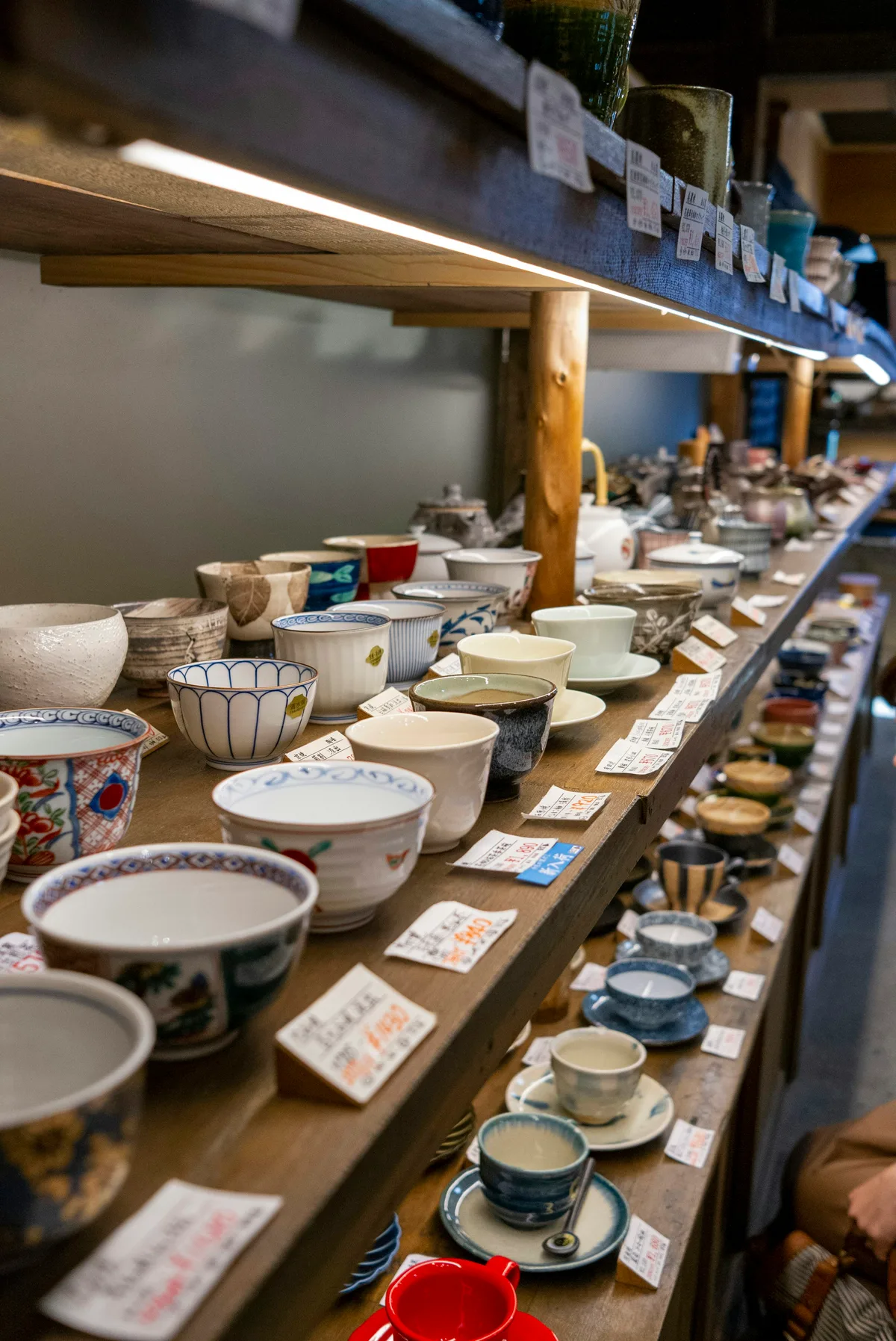 Handmade Japanese ceramic tea wares displayed on wooden shelves in Tokyo