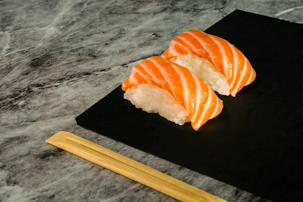 Two carefully presented pieces of nigiri sushi on a dark plate