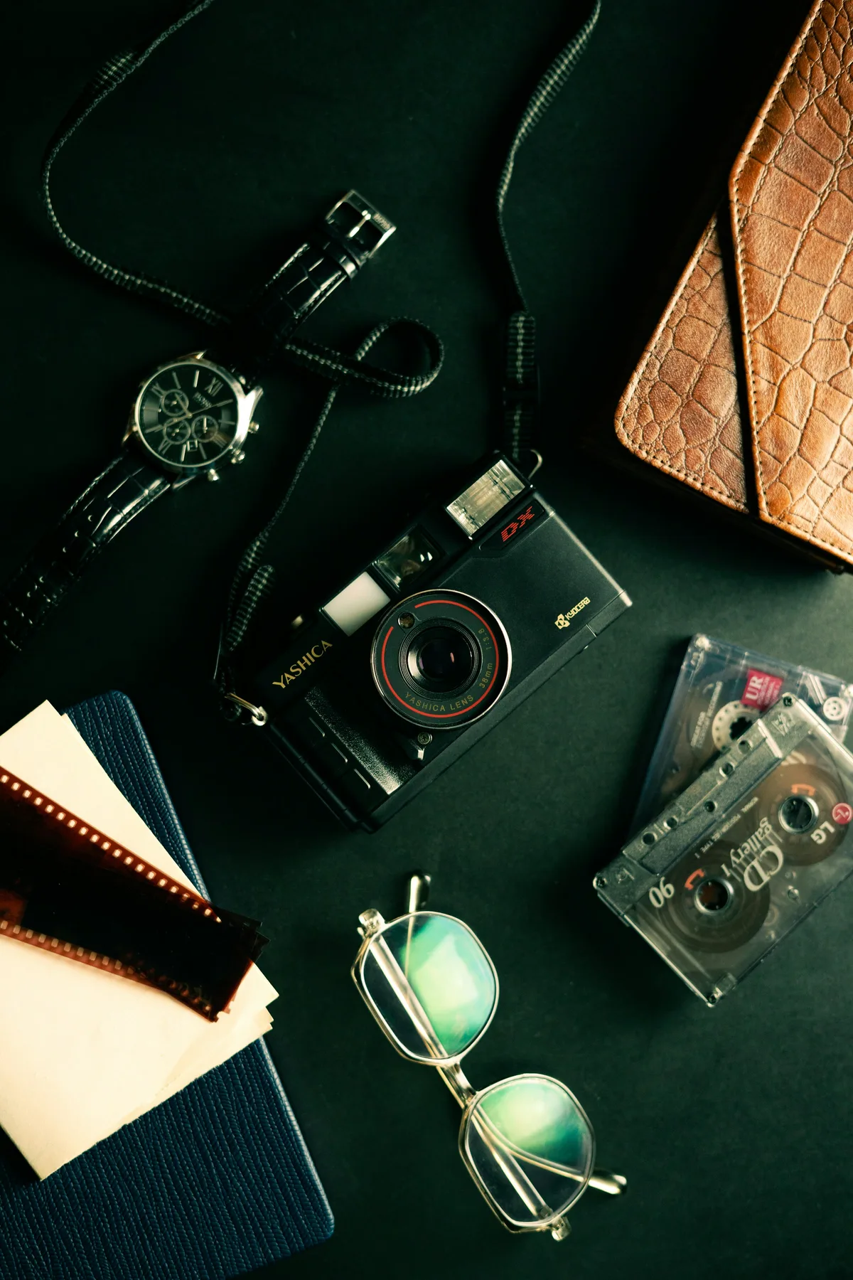 A curated still life of a vintage camera, wristwatch and film